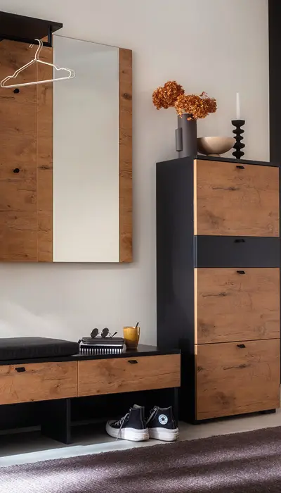 Moderner Eingangsbereich mit Garderobenschrank, Spiegel, Sitzbank und Stauraum in trendiger Holz-Schwarz Kombination, dekoriert mit Trockenblumen und Accessoires für stilvolle Flurgestaltung.